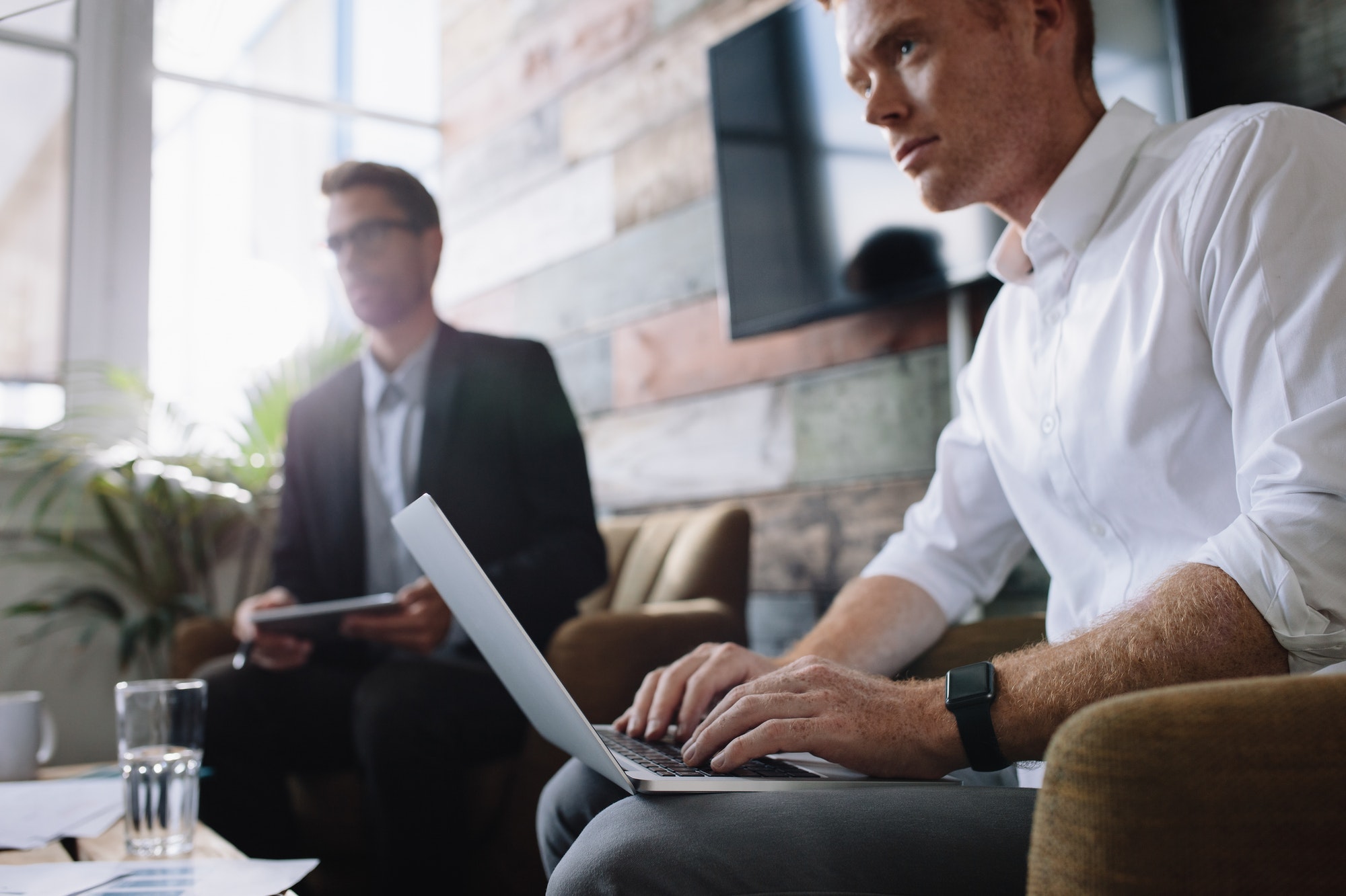 Young businessman working on laptop at corporate meeting